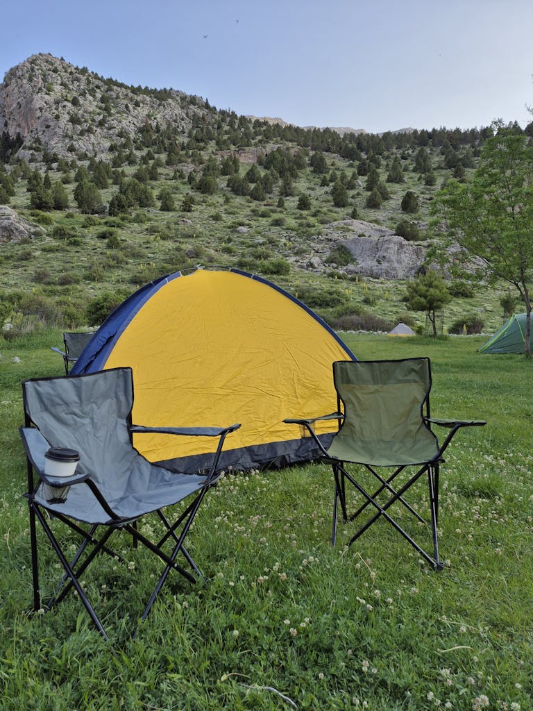 A serene campsite with a tent and chairs against a mountain backdrop, perfect for outdoor adventures.