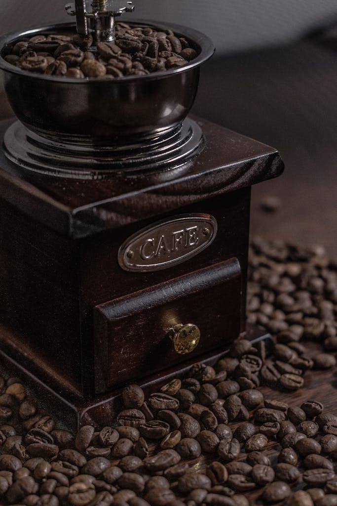 Close-up of an antique coffee grinder surrounded by coffee beans, showcasing rustic charm.