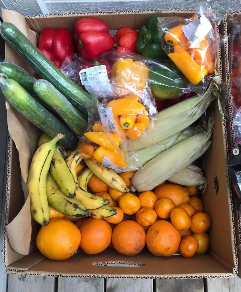 En kartong fylld med räddade frukter och grönsaker från Coop, inklusive paprikor, gurkor, bananer, majskolvar och apelsiner via Svinnbruket Malmö.